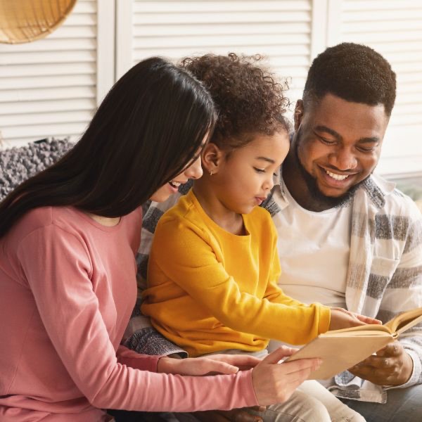 A mother, father and child reading a book together
